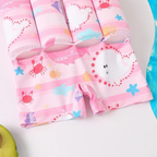 Children's pink swim shorts with cartoon designs on a white background

