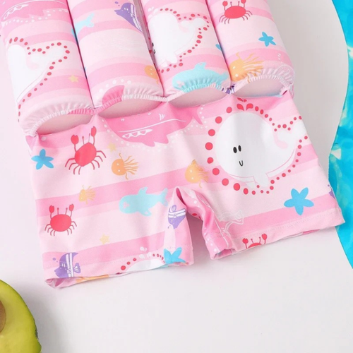 Children's pink swim shorts with cartoon designs on a white background

