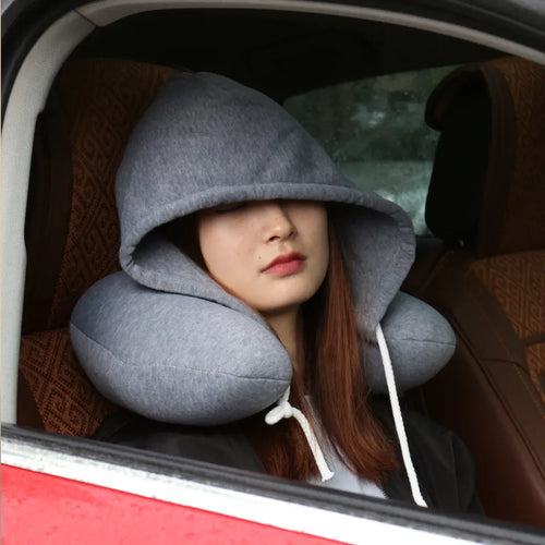 Traveler wearing a hooded neck pillow while resting comfortably in a vehicle.