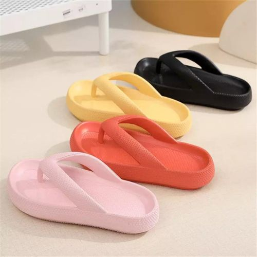 Four colorful flip-flops (black, yellow, red, pink) on a light surface.

