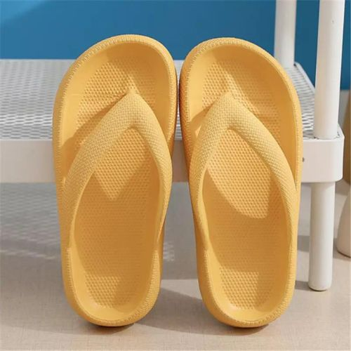 Pair of yellow slippers on a textured surface with a blue background


